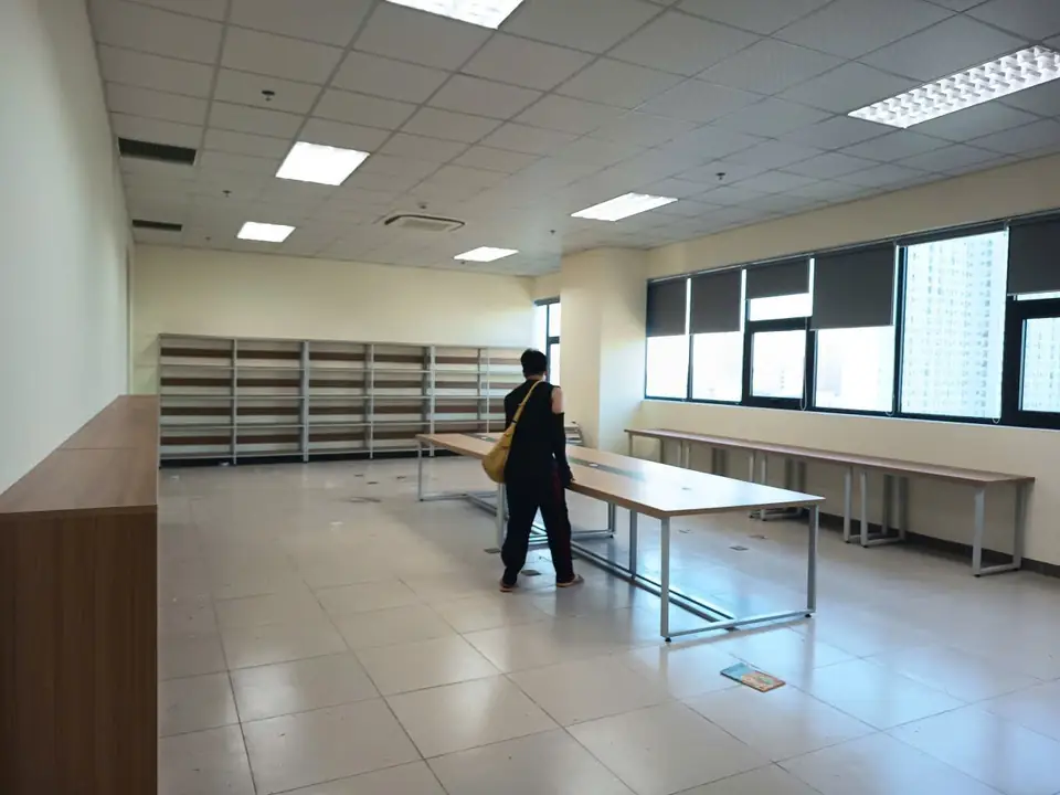Toàn cảnh phòng tài liệu có kệ sắt dựa tường, kệ gỗ bên trái và bàn làm việc dài ở giữa phòng